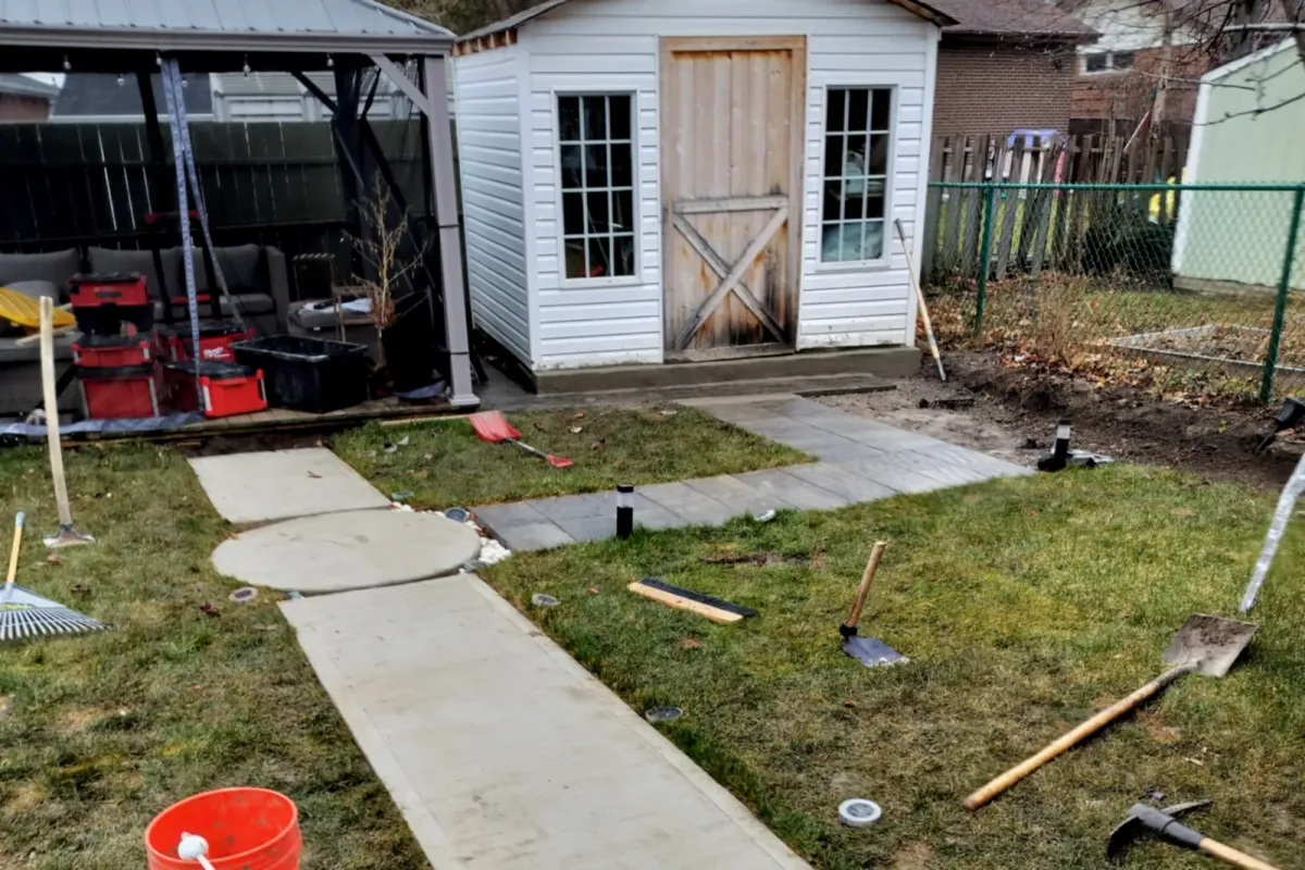 The finished concrete walkway, with a round landing, crossing the lawn to the shed