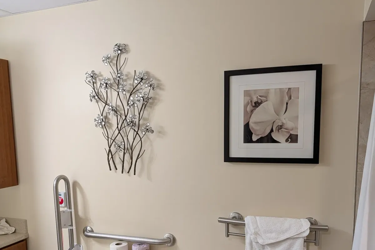 Metal flower wall art and a framed orchid print hung on a bathroom wall