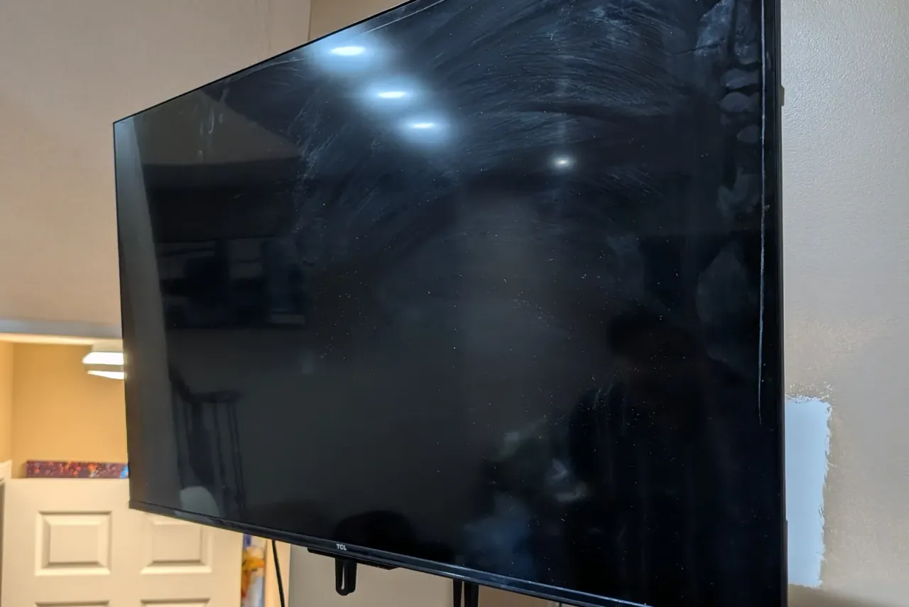 TV on an articulating wall mount in a basement room, with the drywall patched beside it