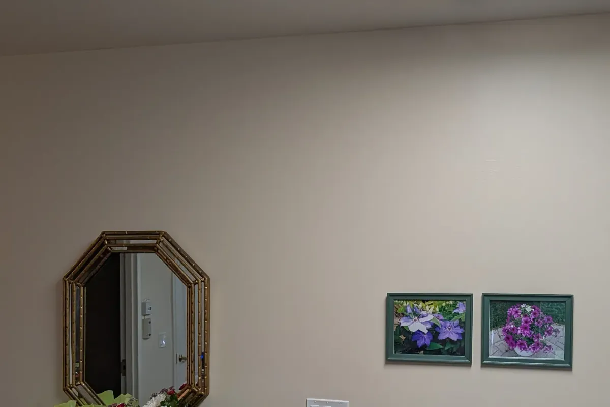 The same entry wall with two framed flower prints hung to the right of the mirror