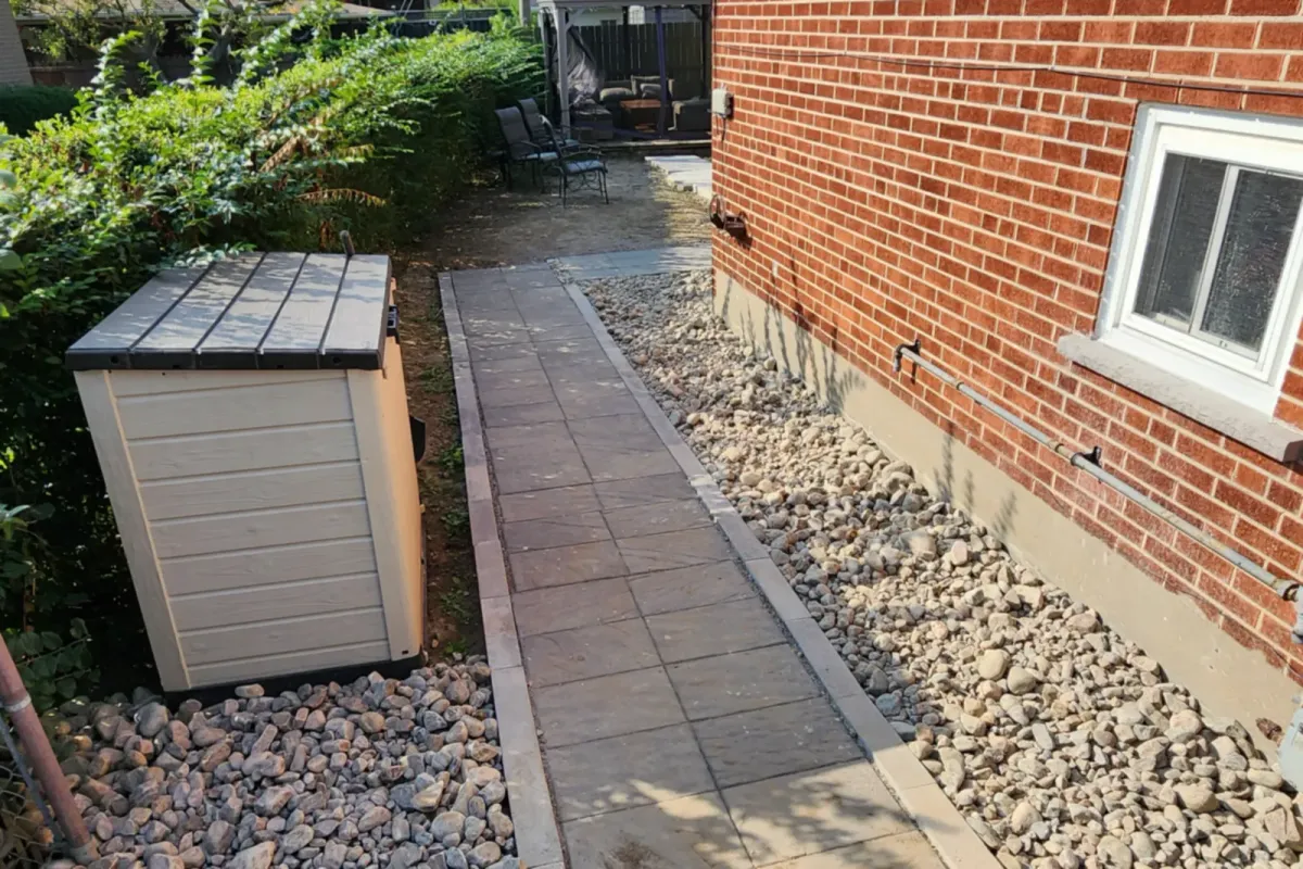 A paved walkway with river-rock borders in its place along the house