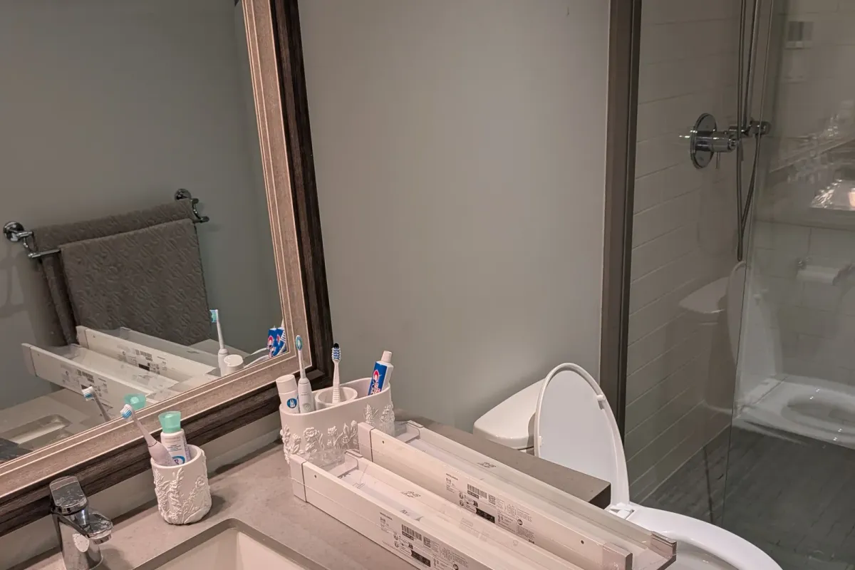 Bathroom wall beside the mirror, with two boxed shelves waiting on the vanity