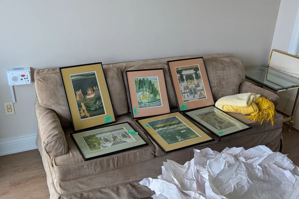 Six framed prints laid out on a sofa, numbered with tape for hanging